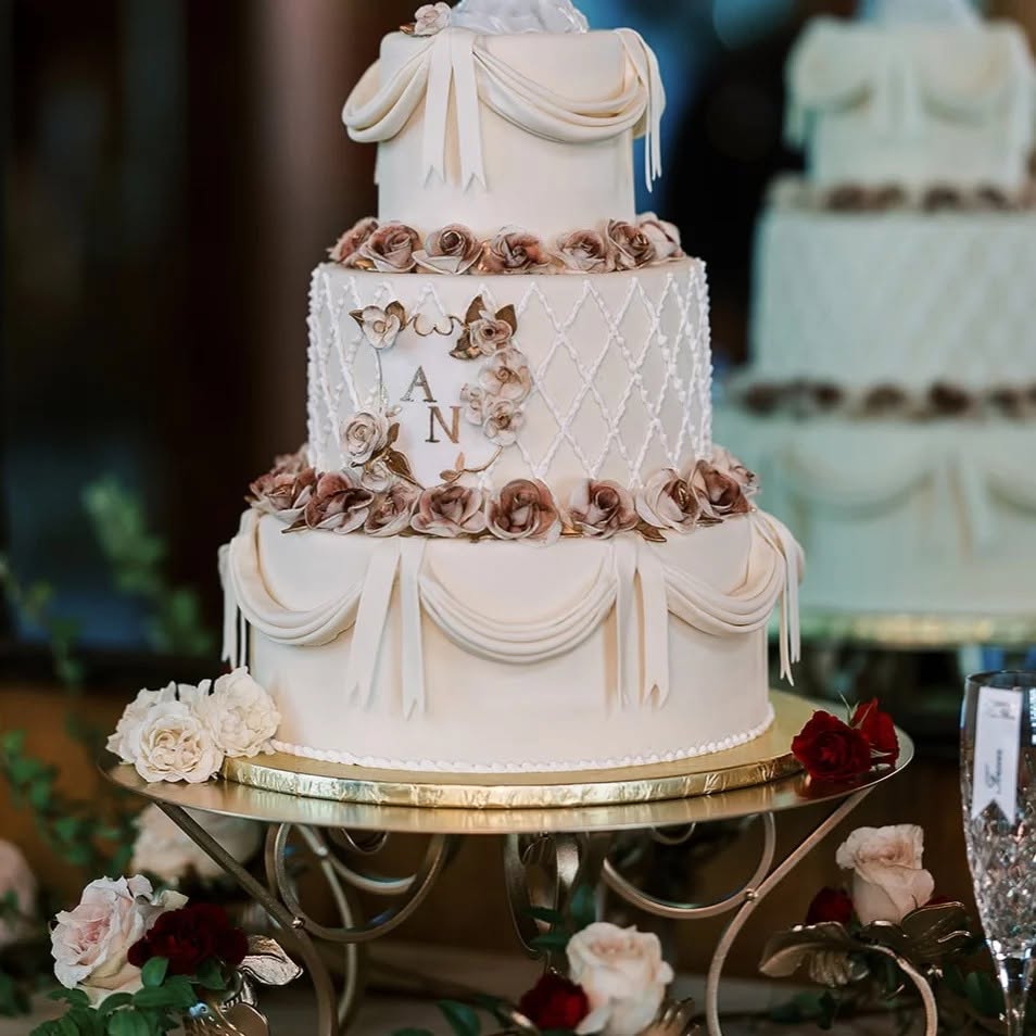 Draped monogrammed wedding cake with roses
